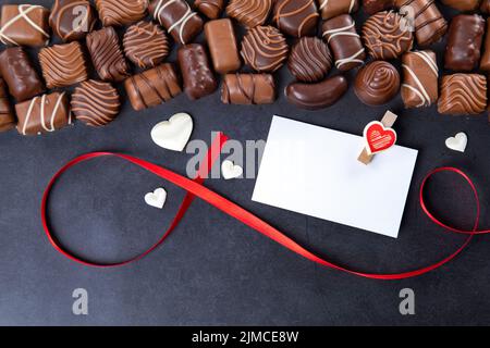 Schokoladenpralinen mit Karte Valentinstag auf schwarzem Hintergrund Stockfoto