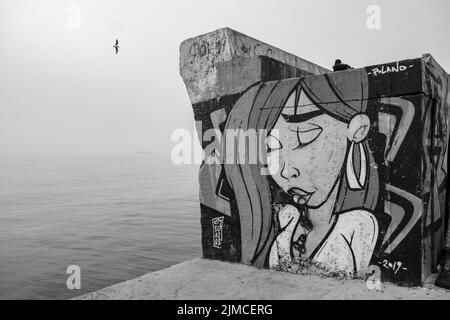 Graffiti, das eine Frau auf einer Betonwand am Meer im Palaio Faliro in Athen, Griechenland, zeigt Stockfoto