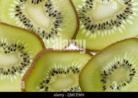 Mehrere Scheiben einer geschnittenen Kiwifrucht im Foto mit Hintergrundbeleuchtung Stockfoto