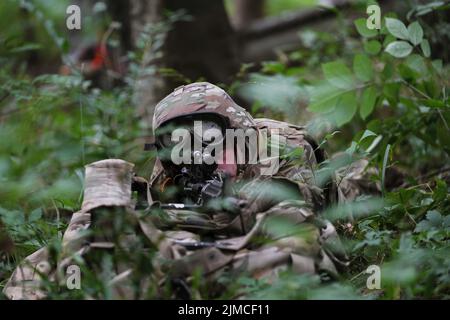 Infanteristen mit der Firma B. 1. Bataillon 151. Infanterie-Regiment führen zusammen mit Kavalleriescouts und Mortarmen städtische Schulungen im Muscatatuck Urban Training Center, Ind., Dienstag, 2. August 2022 durch. Ein Wachmann zieht Sicherheitskräfte an einem simulierten Hubschrauberabsturzort an. Die Teilnahme an realistischen Trainingsszenarien ist die Art und Weise, wie die Indiana National Guard eine tödliche Kampftruppe unterhält. Stockfoto