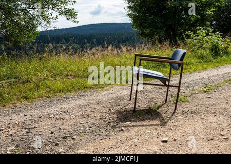 Ein alter kaputte Stuhl auf einer unbefestigten Straße Stockfoto