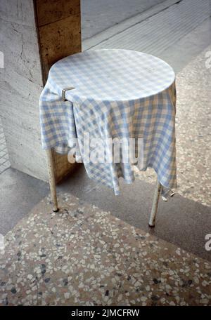 Cafe-Tisch im Freien mit Tischdecke, die von einer Metallklammer gehalten wird Stockfoto