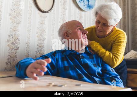 Trauriges, verlorenes und besorgtes kaukasisches Seniorenpaar, das seine letzten Münzen zählte, während es am Tisch saß. Finanzkrise. Niedrige Rente. Hochwertige Fotos Stockfoto