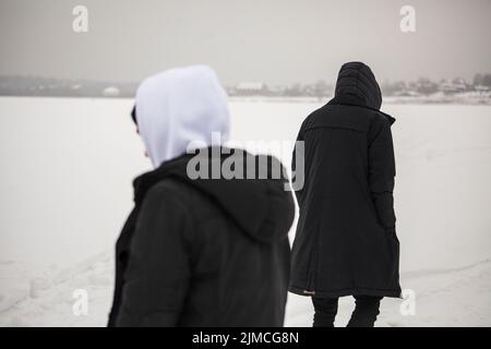 Die Jungs sind auf dem See. Die Menschen laufen auf Eis. Die Jungen stehen im Schnee. Gehen Sie außerhalb der Stadt. Stockfoto