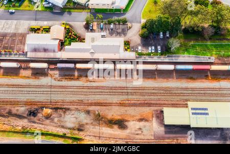 Lokaler Regionalbahnhof in Taree, der Stadt von Australien - von oben aus Sicht auf Plattformen, Terminals, Gleise und Güterzüge. Stockfoto