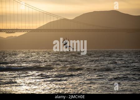 Kite-Surfer, der im Flug unter dem Profil der Golden Gate Bridge hängt und vor der Kulisse der Marin Headlands steht Stockfoto