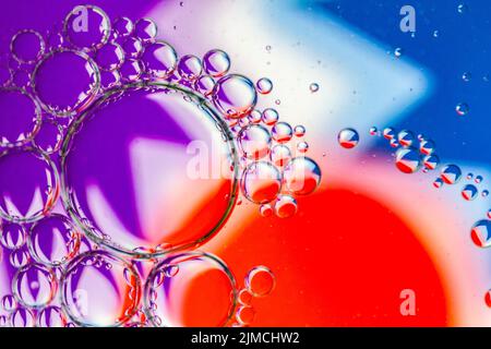 Abstrakter Hintergrund von Ölblasen auf Wasseroberfläche lila rot blau weiß bunte Palette. Stockfoto