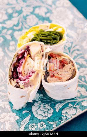 Köstliche Tortilla-Wraps mit verschiedenen leckeren Füllung mit Fleisch, die am Sommertag auf dem Tisch des Café im Freien serviert werden Stockfoto