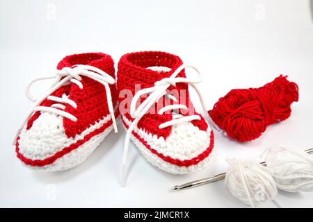 Babyschuhe oder Häkelschuhe in rot und weiß isoliert auf weißem Hintergrund Stockfoto