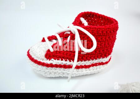 Babyschuhe oder Häkelschuhe in rot und weiß isoliert auf weißem Hintergrund Stockfoto