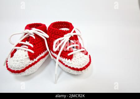 Babyschuhe oder Häkelschuhe in rot und weiß isoliert auf weißem Hintergrund Stockfoto