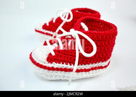 Babyschuhe oder Häkelschuhe in rot und weiß isoliert auf weißem Hintergrund Stockfoto