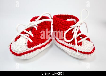 Babyschuhe oder Häkelschuhe in rot und weiß isoliert auf weißem Hintergrund Stockfoto