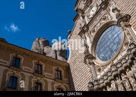 Blick in die verzierte Fassade der Basilika des Montserrat-Klosters: Statuen von Jesus Christus und den zwölf Aposteln. Ein Rosenfenster. Stockfoto