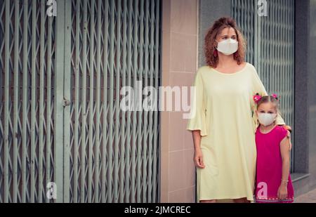 Frau und Tochter tragen eine Einweg-Gesichtsmaske. Coronavirus-Schutz Stockfoto