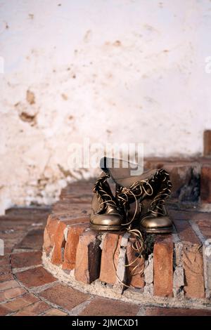 Bronzefarbene Stiefel mit Schnürsenkeln, die an sonnigen Tagen auf der Straße auf schäbigen Ziegeltreppen platziert sind Stockfoto