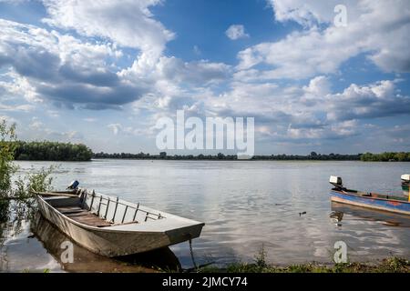 Alte Boote ankern an einem Ufer der Donau in Serbien, an einem sonnigen Nachmittag in Krcedin, Vojvodina. Die Donau ist der größte Fluss in Central Stockfoto