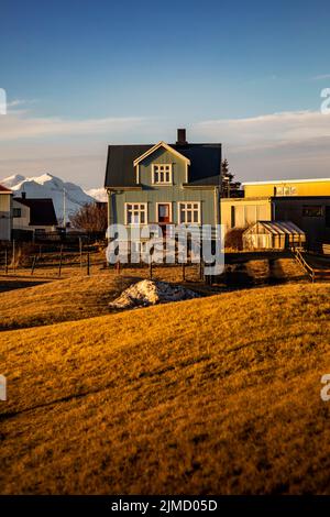 Landschaftlich schöne Aussicht auf Landhäuser im trockenen Tal auf Hintergrund von verschneiten Bergen im Winter in Island Stockfoto