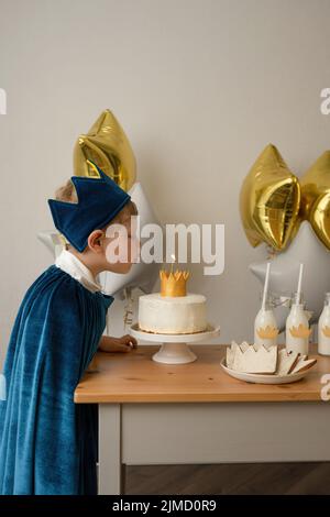 Seitenansicht blonder Junge bläst Kerzen auf einer Geburtstagsparty aus Stockfoto