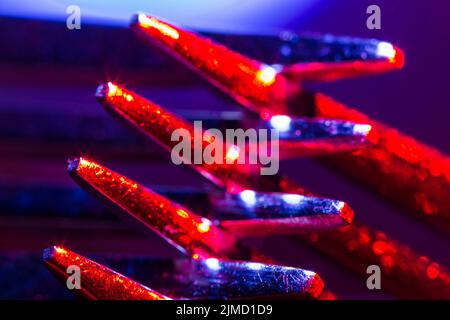 Zwei Gabeln in farbenfroher Makroaufnahme mit Beleuchtung schaffen eine abstrakte Komposition, die sich als Hintergrund eignet. Stockfoto