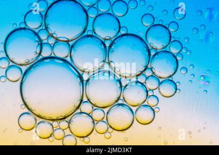 Abstrakter Hintergrund von Ölblasen auf Wasseroberfläche cyan orange bunte Palette. Stockfoto