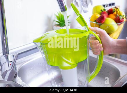 Frau, die den Wasserfilterkrug in der Küche füllte Stockfoto