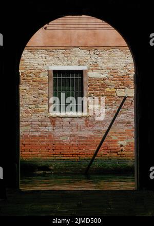 Gewölbte Tür zur alten roten Backsteinmauer und versperrtem Fenster Stockfoto