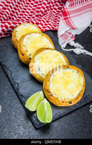 Köstliches libanesisches Essen, sfiha au Gratin mit Labneh und Käse auf schwarzem Schieferstein Hintergrund und Stockfoto