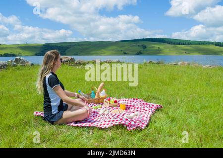 Junge Frau, Picknick auf dem grünen Rasen mit schöner Aussicht Stockfoto