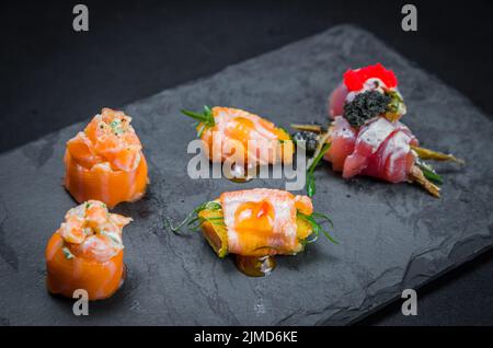 Sushi, traditionelle japanische Küche. Mehrere leckere Sushi auf dem dekorierten Teller, schwarzer Backgroun Stockfoto