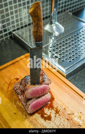 Schönes Foto von Rinderbrisket (Brisket Point End). Fleisch mit geschmiedetem Damaszener Stahlmesser Arkan geschnitten Stockfoto