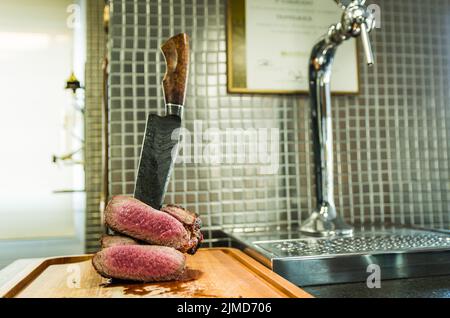 Schönes Foto von Rinderbrisket (Brisket Point End). Fleisch mit geschmiedetem Damaszener Stahlmesser Arkan geschnitten Stockfoto