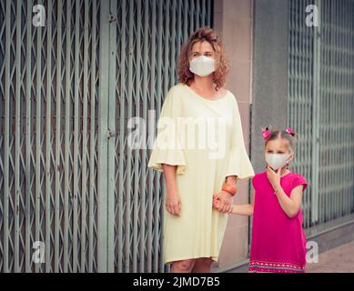 Frau und Tochter tragen eine Einweg-Gesichtsmaske. Coronavirus-Schutz Stockfoto