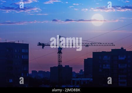 Bau Kran Silhouette gegen Skyline der Stadt, Vollmond über Nacht Stadt Stockfoto