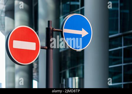 Straßenschilder vor dem Hintergrund des modernen Glasgebäudes Stockfoto