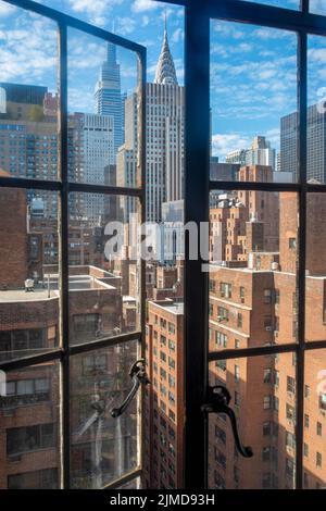 Die Skyline von Manhattan wird durch ein altmodisches, offenes Fenster betrachtet. Stockfoto