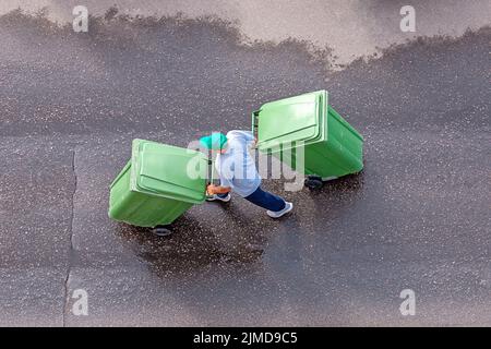 Müllmann bei der Arbeit Transport von Müllcontainern, Draufsicht Stockfoto