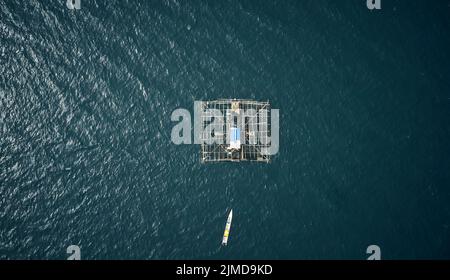 Das Leben in der Nähe der Fische macht sie zu einem einfachen Fang. High-Angle-Aufnahme einer in der Mitte des Ozeans schwimmenden Fischereistruktur namens kelong. Stockfoto