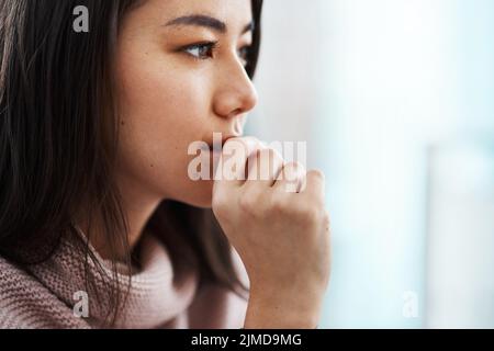 Wen soll ich auf mein Herz oder meinen Geist hören? Eine junge Frau, die sich zu Hause ängstlich fühlt. Stockfoto