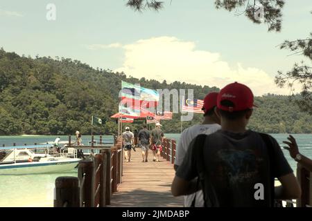 Besucher, die auf einem Steg auf Pulau Sapi (Sapi Island), einem Teil des Tunku Abdul Rahman Parks in Sabah, Malaysia, spazieren gehen. Stockfoto