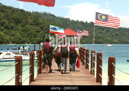 Eine Gruppe von Journalisten, die während einer von Air Asia organisierten Medienreise im Gebiet des Tunku Abdul Rahman Parks in Sabah, Malaysia, auf einem Steg auf der Insel Pulau Sapi (Sapi Island) spazieren gehen. Stockfoto