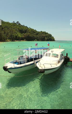 Ein Touristenboot auf dem Küstenwasser von Pulau Sapi (Sapi Insel), einem Teil des Tunku Abdul Rahman Parks in Sabah, Malaysia. Stockfoto