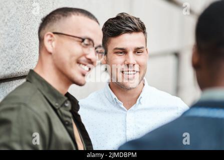 Es lohnt sich, solche Geschäftsverbindungen zu haben. Drei junge Geschäftsleute, die vor städtischem Hintergrund diskutieren. Stockfoto