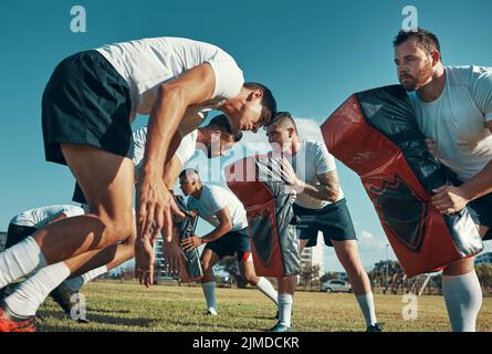 Training zum Champion. Eine Gruppe Rugby-Spieler trainiert mit Tackle Bags auf dem Feld. Stockfoto