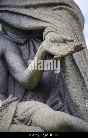 Nahaufnahme von Maria, die Jesu Hand mit Stigmata in der Friedhofsstatue hält. Stockfoto