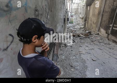 Gaza, Palästina. 05. August 2022. Ein palästinensischer Junge steht nach einem israelischen Luftangriff in der Nähe eines Gebäudes. Der hochrangige Kommandeur des Islamischen Dschihad wurde bei einem israelischen Luftangriff getötet, teilte die palästinensische militante Gruppe mit. „Die Bewegung des Islamischen Jihad in Palästina und ihr militärischer Flügel, die Al-Quds Brigade, trauern um den großen dschihadistischen Kommandanten Tayseer al-Jabari 'Abu Mahmud', der bei einem zionistischen Attentat getötet wurde.“ (Foto von Mahmoud Issa/SOPA Images/Sipa USA) Quelle: SIPA USA/Alamy Live News Stockfoto