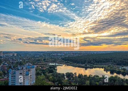 Blick auf Petropavlivska Borshchagivka Dorf, Teich und einen großen immergrünen Wald am Stadtrand von Kiew, Ukraine bei Sonnenuntergang Stockfoto