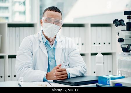 Vertuschen Sie sich, Ihre Sicherheit zählt darauf. Porträt eines jungen Wissenschaftlers, der einen Laptop benutzt, während er an einer Coronavirus-Heilung in einem Labor arbeitet. Stockfoto