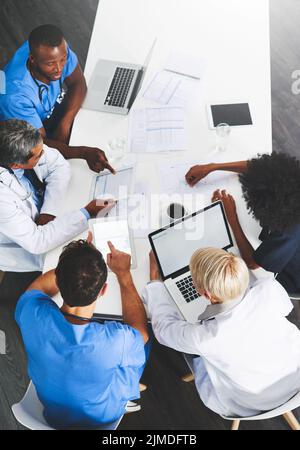 Ärzte, medizinische Fachkräfte oder Mitarbeiter im Gesundheitswesen mit einem Laptop sprechen, treffen oder planen medizinische Behandlung im Krankenhaus. Über der Ansicht der verschiedenen Gruppe Stockfoto