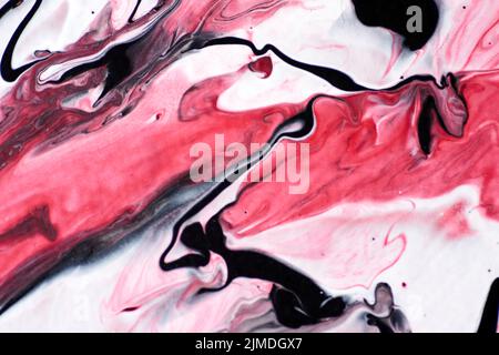 Marmoriertes Acrylfarbenmuster in den Farben rot, schwarz, weiß und pink. Stockfoto